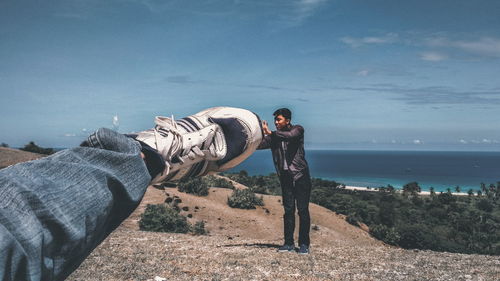 Man touching large shoe against sea