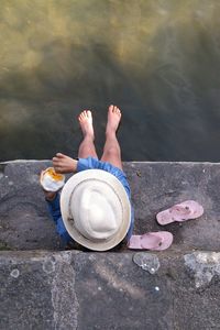 Low section of man sitting by lake