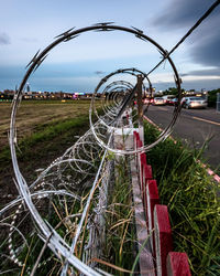 Metallic fence on field against sky