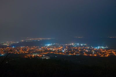 Illuminated cityscape against sky at night