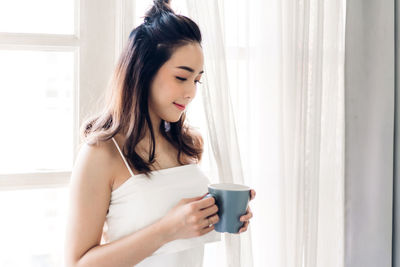 Beautiful young woman drinking coffee cup at home