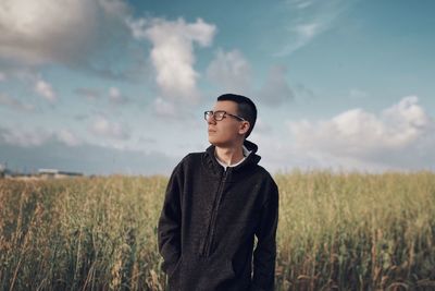 Man looking away on field against sky