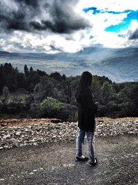 Rear view of woman standing on mountain against sky