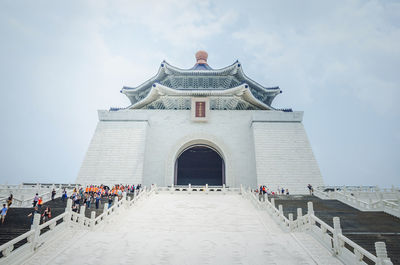 Group of people outside temple against sky