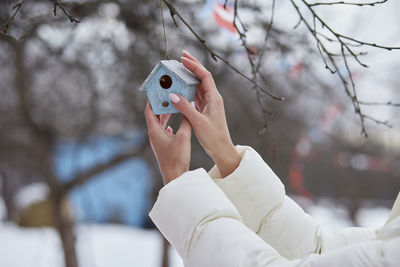 Woman decorating home yard with handmade toys. winter weather outside. seasonal traditions.