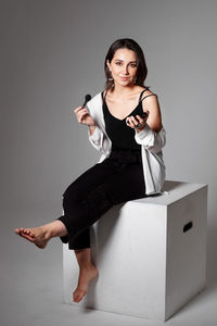 Portrait of a young woman sitting on wall