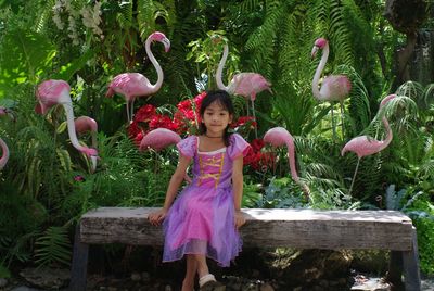 Portrait of happy girl standing by pink plants