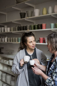 Female potters discussing with coffee cups in ceramics workshop