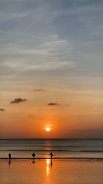 Silhouette people on beach against sky during sunset