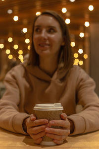 A cup of coffee in the hands of a girl sitting at a table on a food court