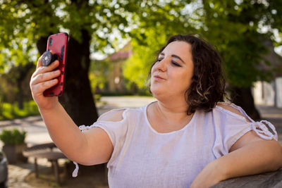 Young woman using mobile phone while sitting outdoors