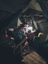 Man reading book while sitting in tent