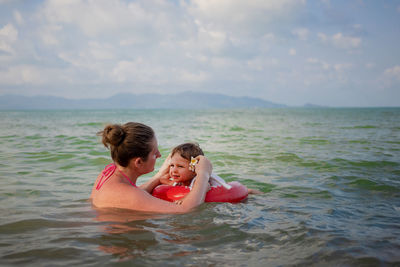 Rear view of mother and daughter in sea