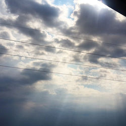 Low angle view of power lines against cloudy sky