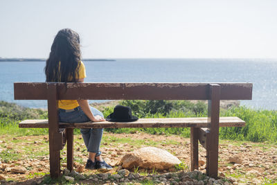 Rear view of woman sitting on bench at park