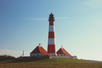 Lighthouse on field against blue sky