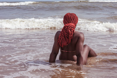 African woman sitting on the sea shore with red hair in ghana west africa