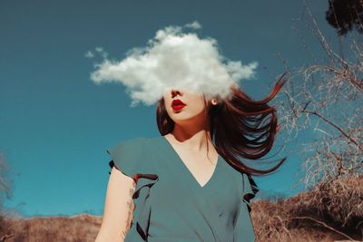 Young woman smoking against sky