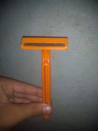 Close-up of hand holding orange wall