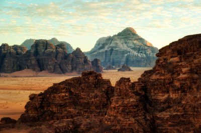 Rock formations on landscape against cloudy sky