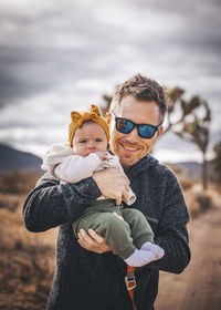 A man with a baby is standing in a desert of california