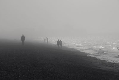 Silhouette men on beach against sky