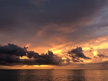 Scenic view of sea against dramatic sky during sunset