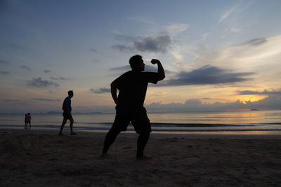 Full length of man practicing on beach against sky during sunset