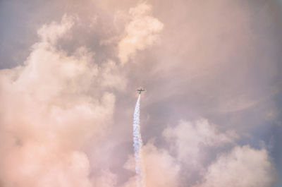 Low angle view of airplane flying in cloudy sky