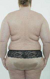 Rear view of shirtless man standing against white background