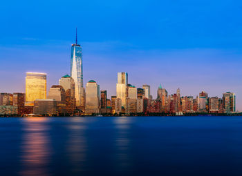 Illuminated buildings in city against blue sky