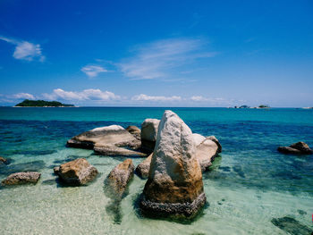 Rocks in sea against blue sky