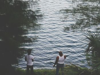 Rear view of people standing by sea against sky