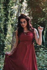 Portrait of young woman standing against trees