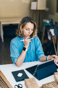 Young woman using phone while sitting on table