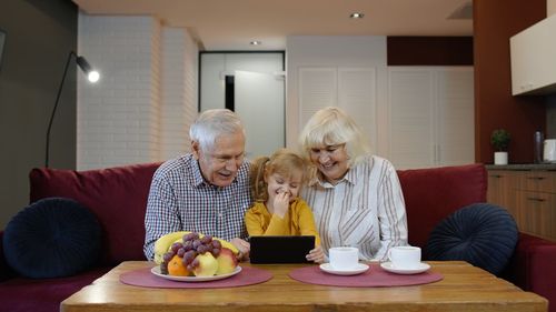 Grandparent with granddaughter using digital tablet at home
