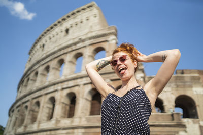 Low angle view of smiling young woman against sky