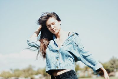 Young woman standing against sky