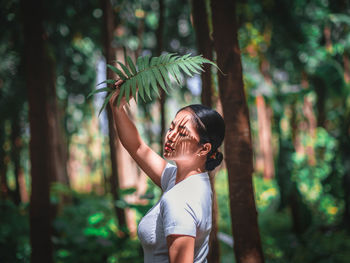 Midsection of woman standing by tree in forest