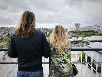 Rear view of woman standing by railing against sky