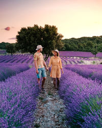 Rear view of women standing on purple flower on field against sky