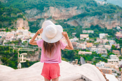 Rear view of woman wearing hat standing against city