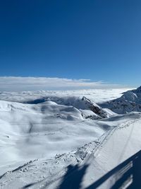 Scenic view of snow covered mountains against blue sky