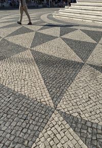 Low section of person walking on cobblestone street