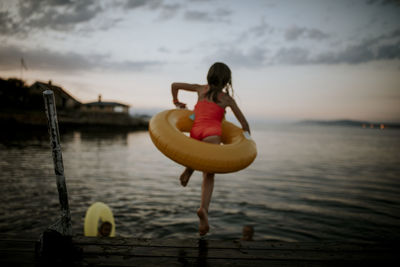 Girl with inflatable ring jumping into water