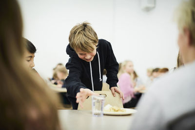 Boy picking up glass of drinking water in school cafeteria