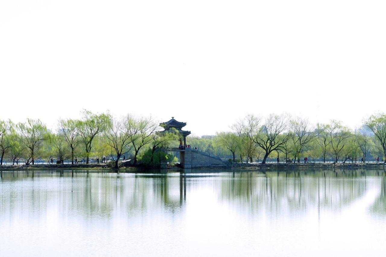 clear sky, water, tree, reflection, copy space, waterfront, lake, tranquility, tranquil scene, scenics, nature, river, beauty in nature, day, outdoors, standing water, calm, idyllic, mid distance, growth