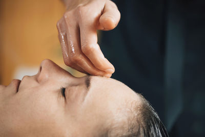 Woman enjoying ayurvedic head and forehead massage therapy with essential oil in spa room