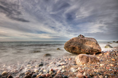 View of calm beach against cloudy sky