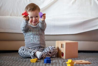 Full length of happy boy with down syndrome playing on rug at home